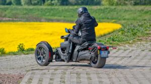 Moto 3 roues dans un champs de fleurs jaunes.