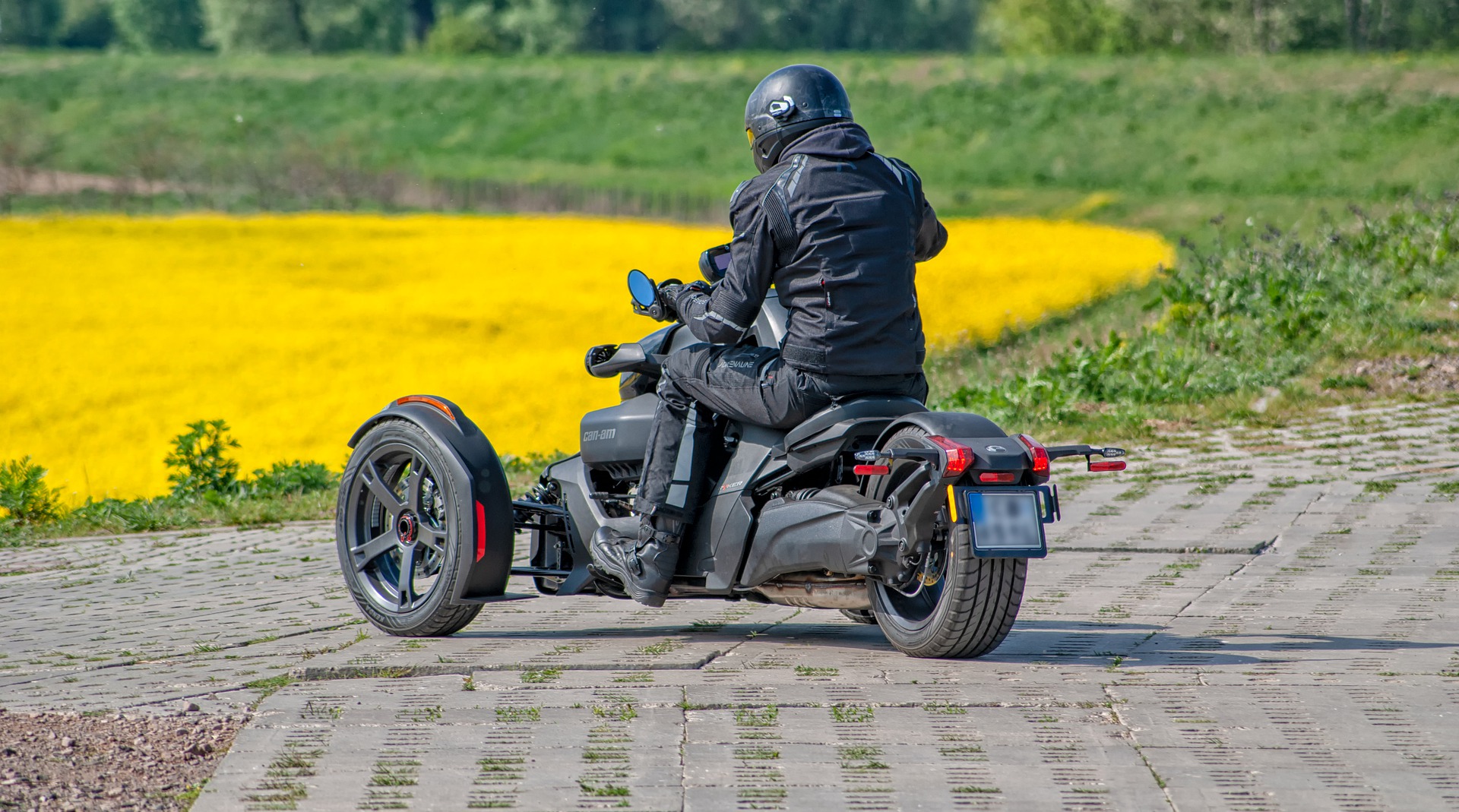 Moto 3 roues dans un champs de fleurs jaunes.